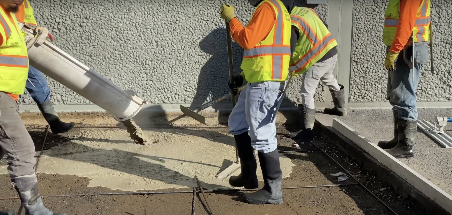 Construction workers in safety gear pouring concrete
